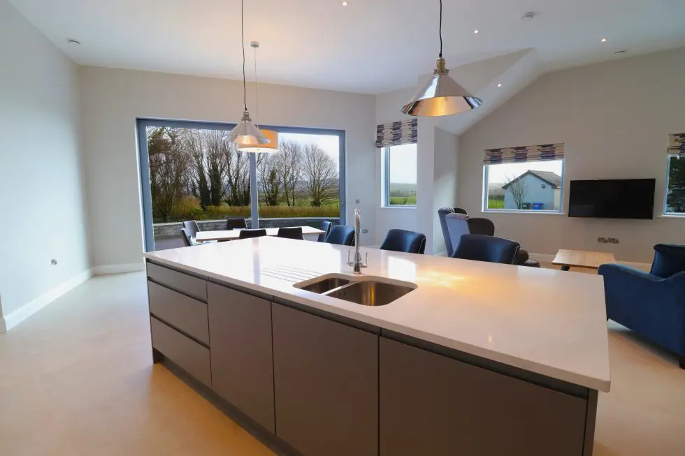 Modern kitchen with island and large windows.